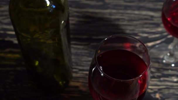 Bottle and glass of red wine on a wooden table - Filmati, video