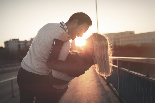 Пара цілується в місті під час заходу сонця
 - Фото, зображення