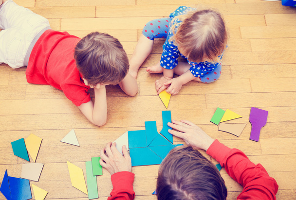учитель и дети играют с геометрическими фигурами
 - Фото, изображение
