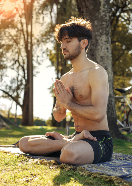 Nuori mies meditoi puistossa lootusasennossa
 - Valokuva, kuva