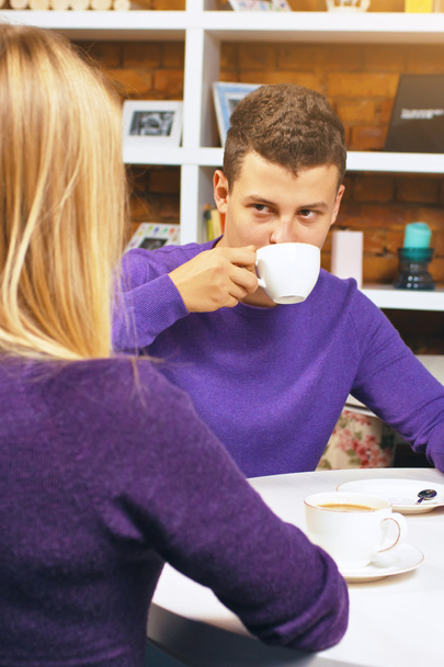 Νεαρός άνδρας, πίνοντας καφέ και να συνομιλεί με μια γυναίκα. Ωραίο να συναντήσετε φίλους ή εραστές. - Φωτογραφία, εικόνα