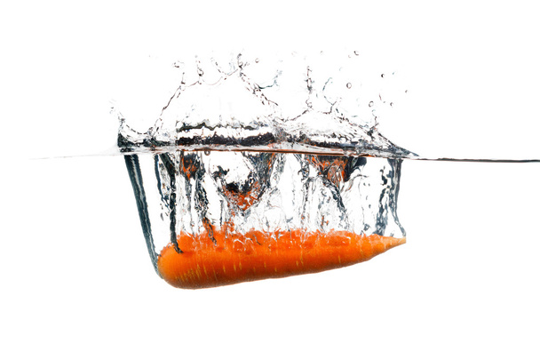 Carrot in the water splash over white background. - Фото, зображення