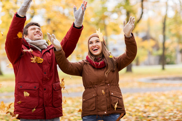 feliz pareja joven lanzando hojas de otoño en el parque
 - Foto, Imagen