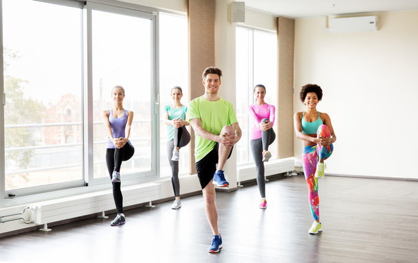 group of smiling people exercising in gym - Foto, Bild