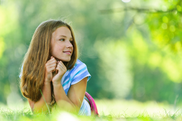 tienermeisje in blauwe blouse liggen op gras - Foto, afbeelding