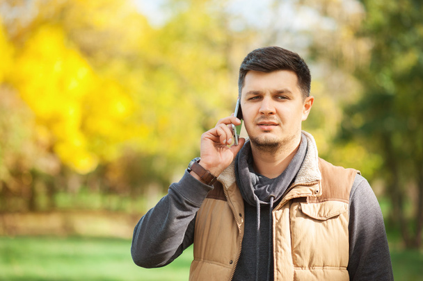 Young man in park speaking on the smart phone - Fotó, kép