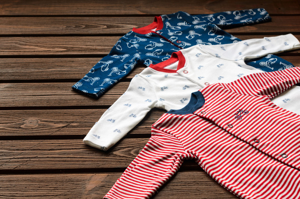 Baby boy clothes (sleepsuits) on brown wooden background - Φωτογραφία, εικόνα