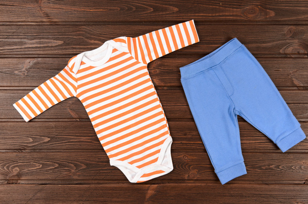 Combinaisons et pantalons pour bébés sur fond en bois. Vêtements bébé
 - Photo, image