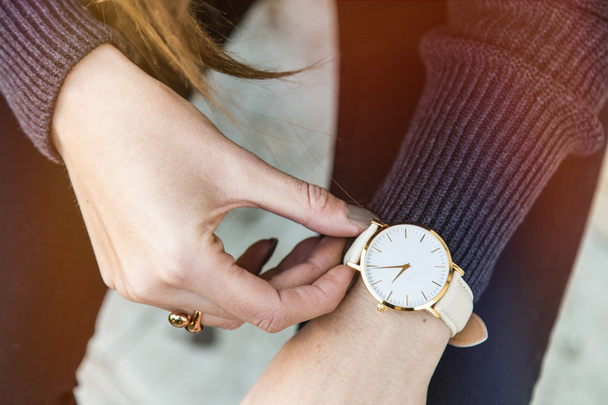 close up fashion details, young business woman holding her golden watch. graded in warm colors. - Photo, Image
