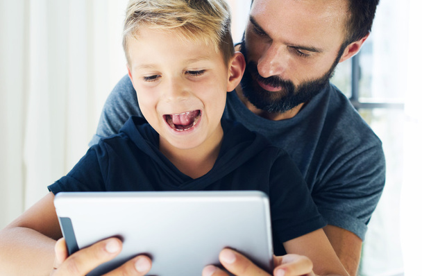 Closeup of young boy sitting with father at the table and using pc tablet in modern loft. Horizontal, blurred background. - Foto, Bild