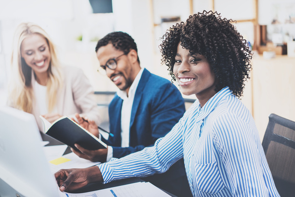 Group of three coworkers working together on business project in modern office.Young attractive african woman smiling, teamwork concept. Horizontal, blurred background. - Valokuva, kuva