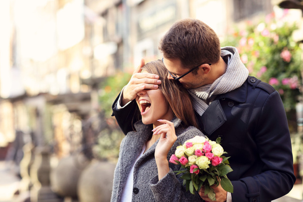 Young man surprising woman with flowers - 写真・画像