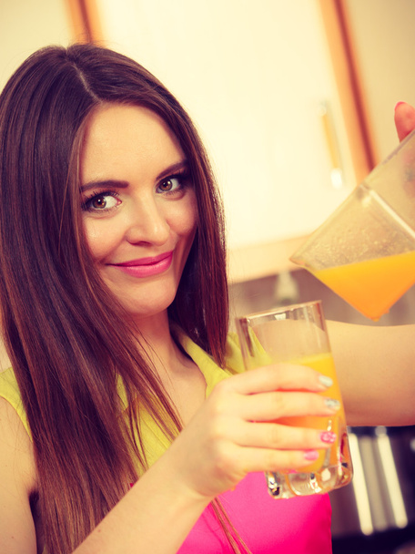 Woman make orange juice in juicer machine pouring drink in glass  - Photo, Image