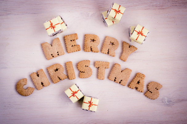 Ajándék csokoládé és keksz készült betűkkel "Boldog karácsonyt". Tónusú kép. - Fotó, kép