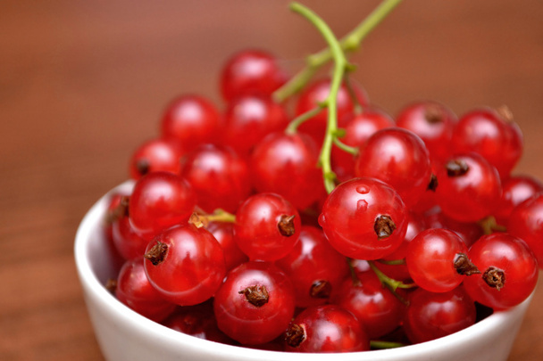 Red currant in the plate on the table. - Фото, зображення