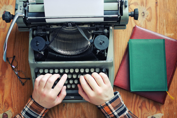 Ретро-рука пишущей машинки на деревянном столе
 - Фото, изображение