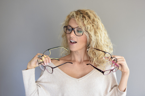 woman  choosing between different eyeglasses - Foto, afbeelding
