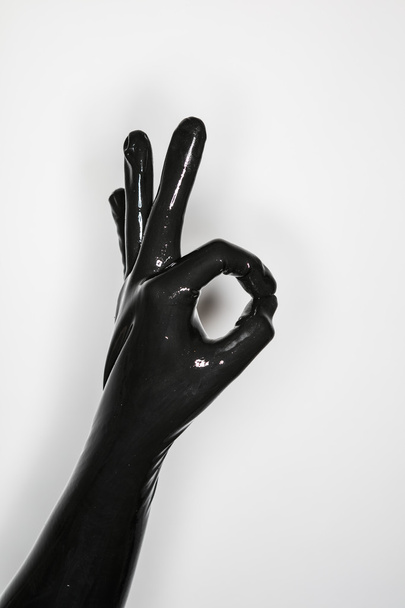 χειρονομία του ενός χεριού, φορώντας ένα μαύρο γάντι λατέξ, σηματοδότησης εντάξει - Φωτογραφία, εικόνα