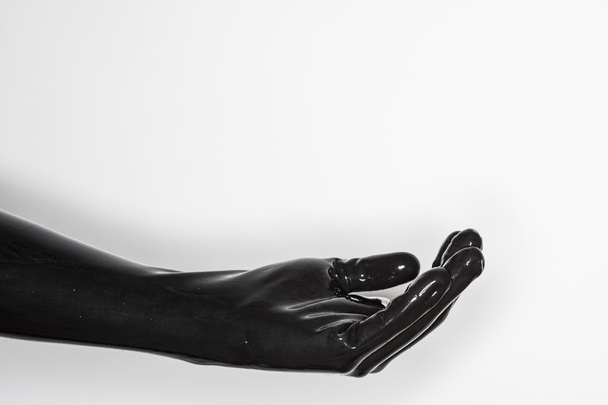 gebaar van een hand, het dragen van een zwarte latex handschoen: aanbieden  - Foto, afbeelding