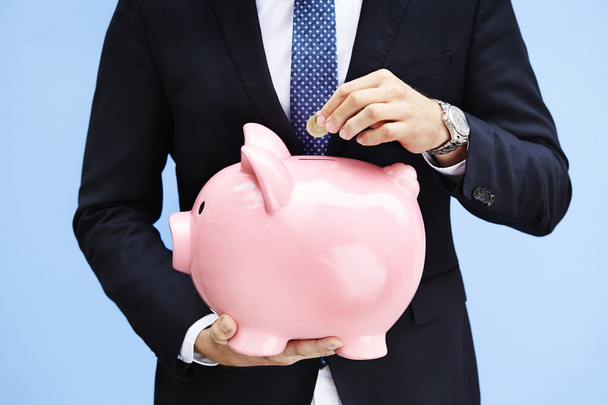 Saving money in piggy bank - Фото, изображение