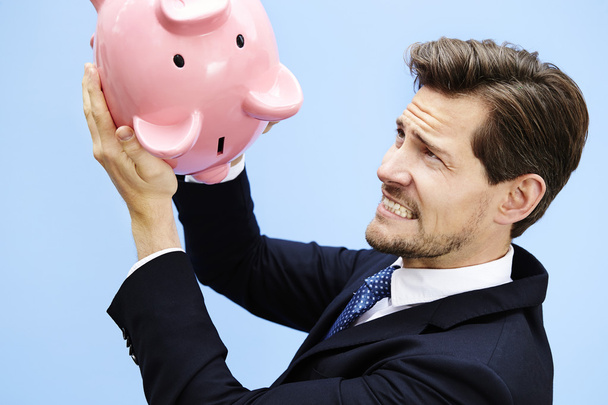 Businessman shaking piggy bank - Фото, изображение