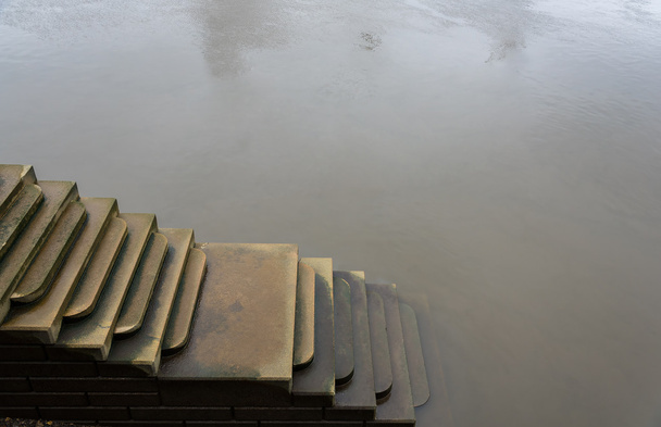 Nastrojowy sceny schodach prowadzących w dół w złowrogi wody. - Zdjęcie, obraz