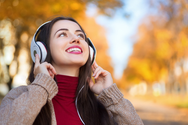 Autumn portrait of happy woman with headphones in park - Foto, imagen