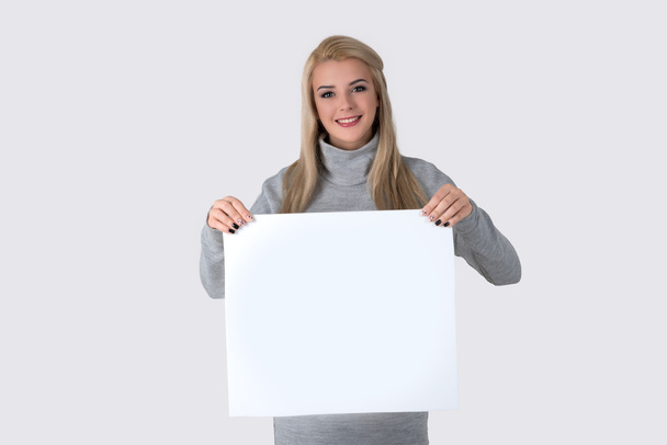 la joven sostiene una hoja de papel limpia
 - Foto, imagen