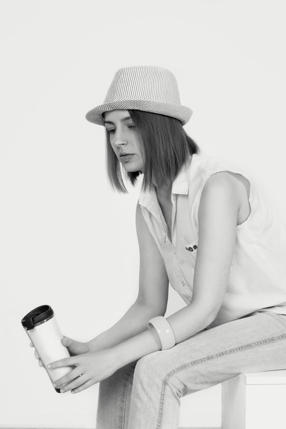 the young woman sits with a thermocup with coffee - Photo, Image