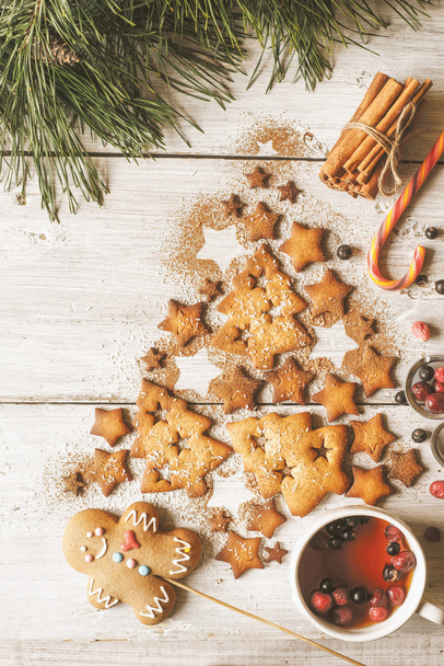 Kerstboom gemaakt door cookies en kaneel op de witte houten tafel met berry thee verticale - Foto, afbeelding