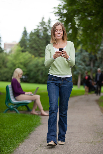 Woman Reading Text Message In Park - Zdjęcie, obraz