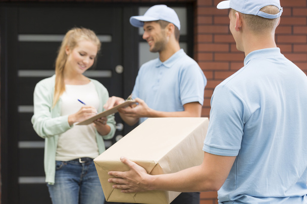 Courier with package and woman signing a form - Foto, Bild
