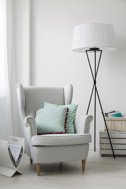 Stijlvolle grijze fauteuil en een staande vloerlamp - Foto, afbeelding