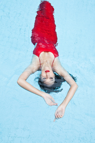 Kobieta w czerwonej sukience pływanie w basenie - Zdjęcie, obraz