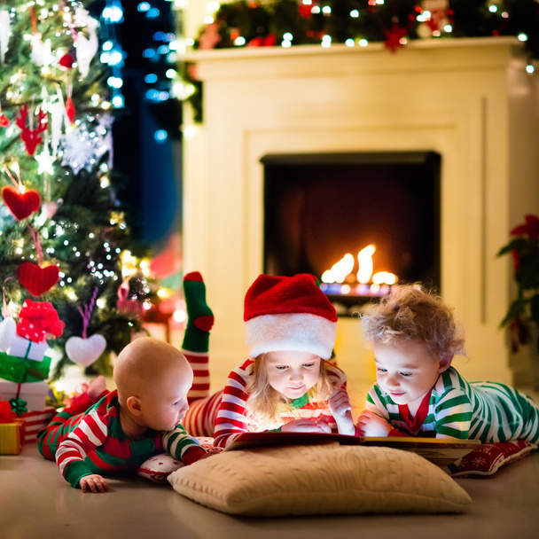 クリスマス ツリーの下のパジャマを着て子供たち - 写真・画像