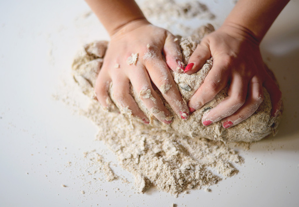 Woman's hands knead dough on a table - Foto, imagen