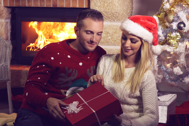 Young couple opening a Christmas present  - 写真・画像