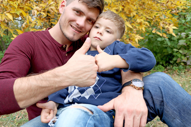 Ojciec trzyma jego syna w jego ramiona, ojciec i syn razem bawiąc się na zewnątrz w drewnie - Zdjęcie, obraz