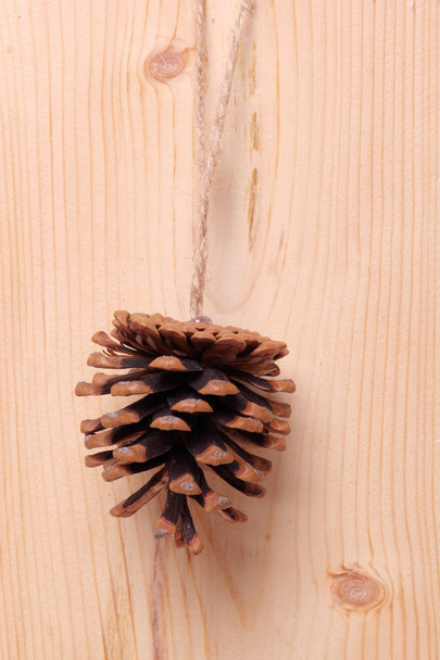 Cono di pino con fiocco su sfondo in legno
. - Foto, immagini