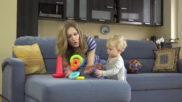 Mom with toddler daughter girl put toy circles on hands like bracelets. - Záběry, video