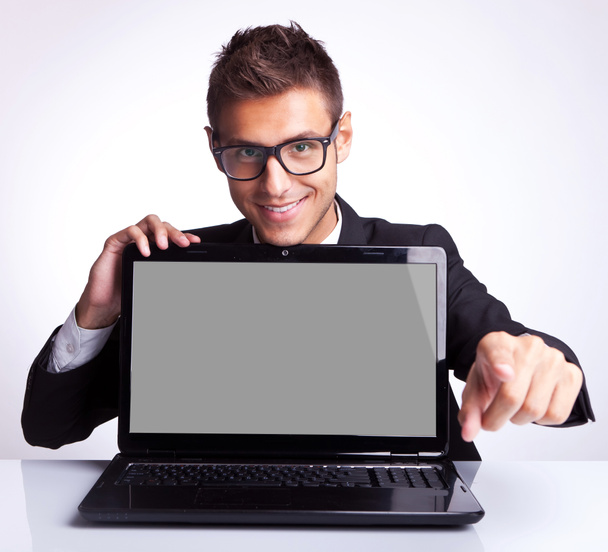 Hombre sentado en el escritorio de la oficina con el ordenador portátil señalando - Foto, Imagen
