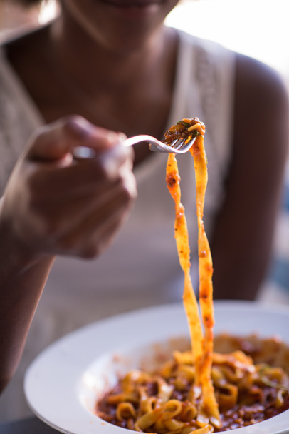 una joven afroamericana comiendo pasta
 - Foto, Imagen
