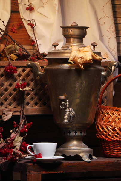 Samovar avec une tasse de thé. / Une tasse de thé et un samovar russe sous la lumière d'une lanterne. Automne
. - Photo, image