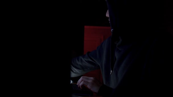 Hacker in hood cracking code using computers in dark room - Metraje, vídeo