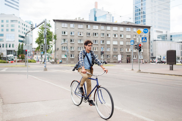 young hipster man with bag riding fixed gear bike - Fotó, kép
