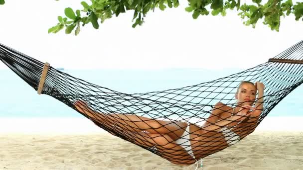 Beautiful woman full of vitality reclining suntanning in a hammock - Footage, Video