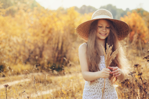 happy kid girl in straw having fun on summer field. Summer outdoor activities with children - Foto, afbeelding