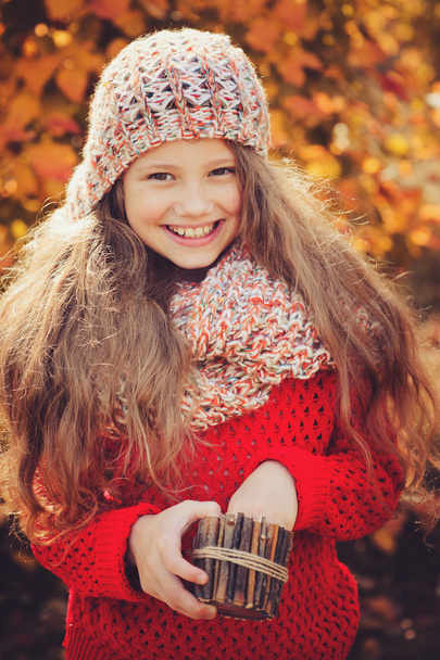 happy child girl in knitted scarf and sweater with basket on autumn walk in forest - Foto, imagen