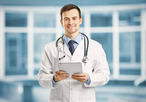 Professional male doctor with tablet on blurred hospital background, Gynecology concept - Фото, изображение