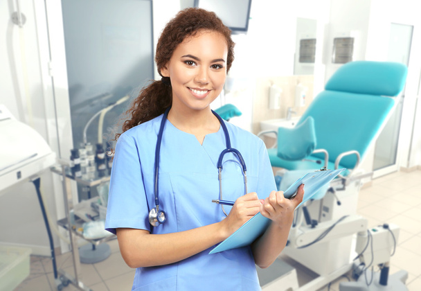 Professional female doctor with clipboard on blurred consulting room background, Gynecology concept  - Photo, Image